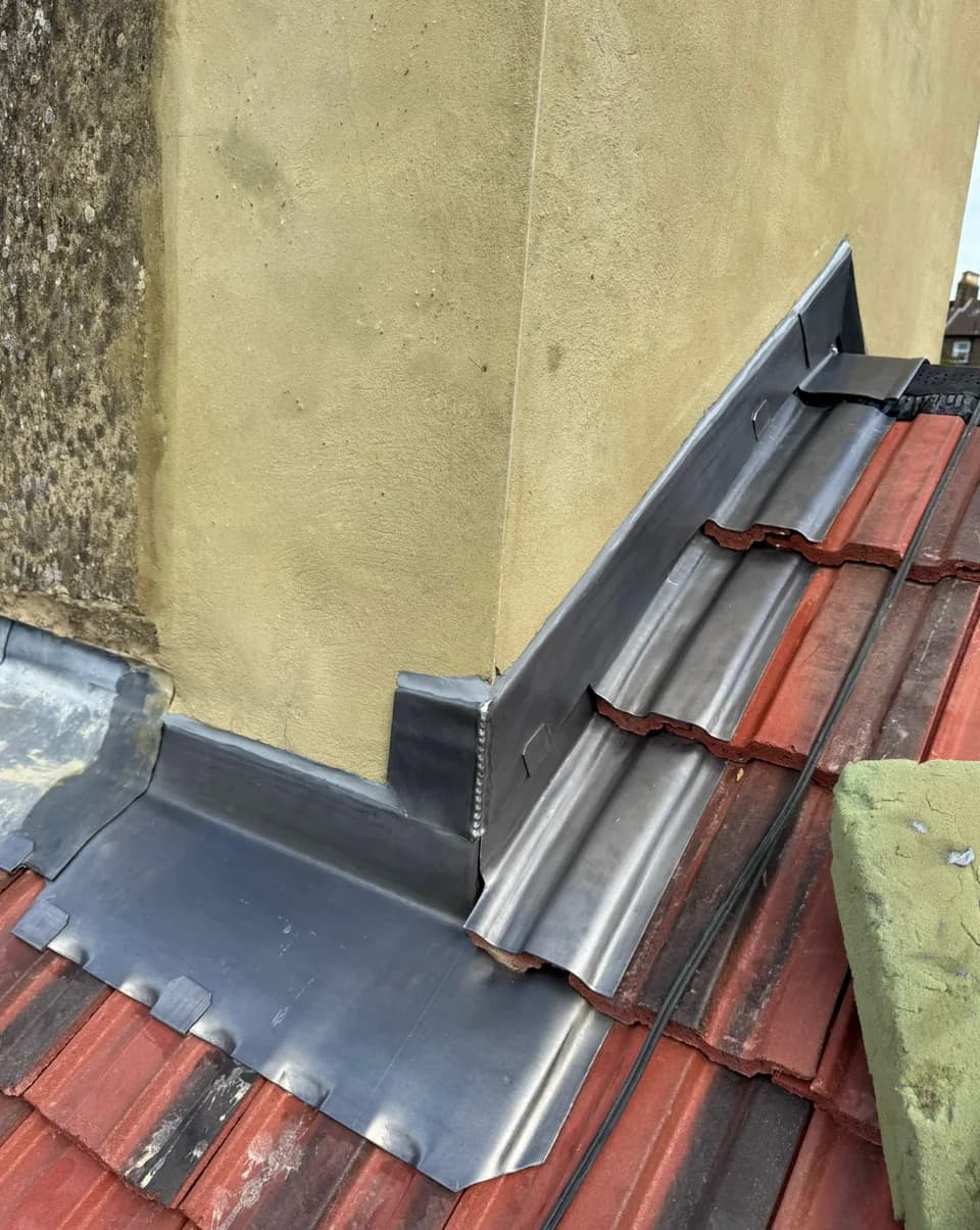 Welded lead apron and stepped flashing where roof tiles meet a wall