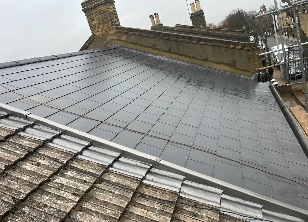 New slate covering laid beside an existing tiled roof