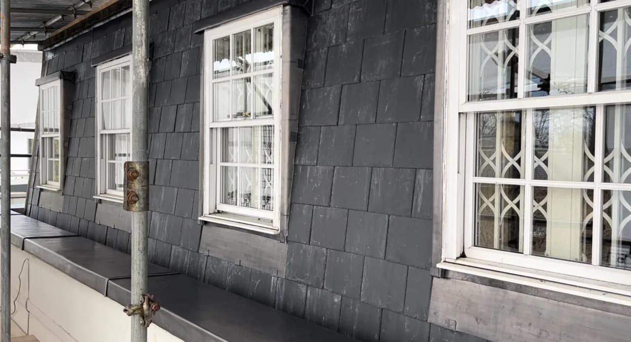 Vertical slate hanging protecting a wall beneath windows
